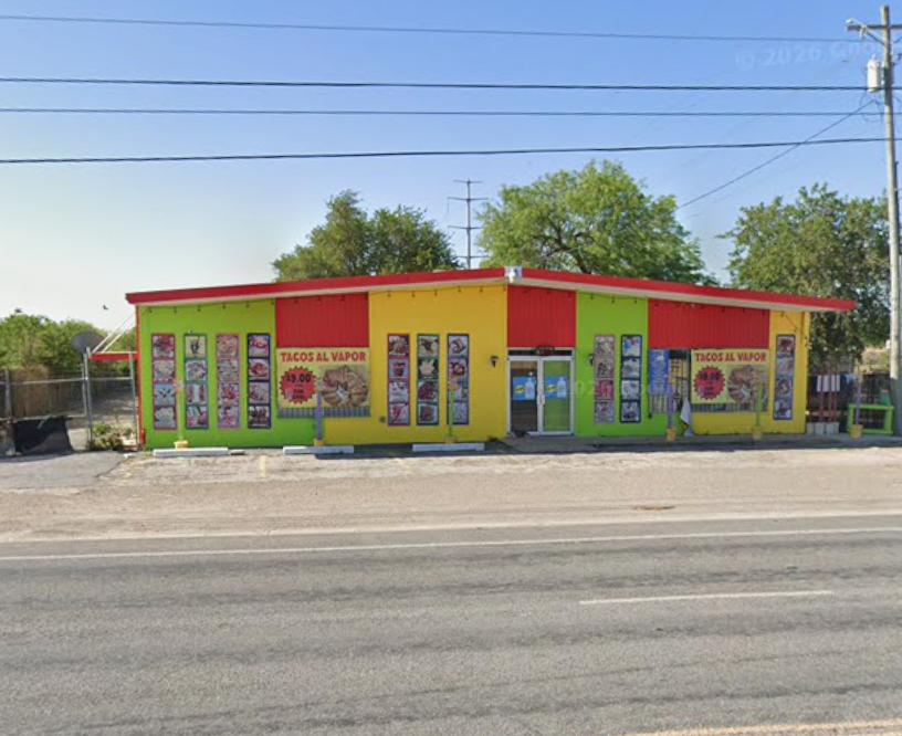 Fachada del restaurante pintada de verde limón y amarillo con techo rojo, junto a la carretera.
