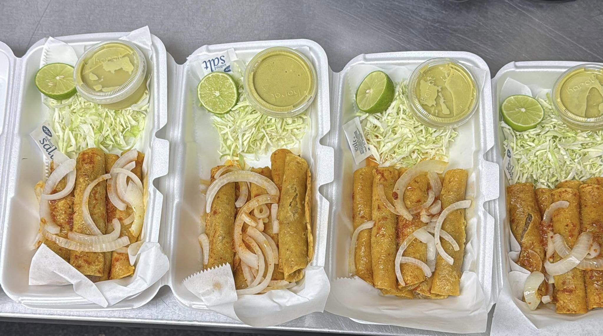 Órdenes de tacos al vapor recién servidas, con cebolla en rodajas, repollo rallado, mitad de limón y salsa aparte.